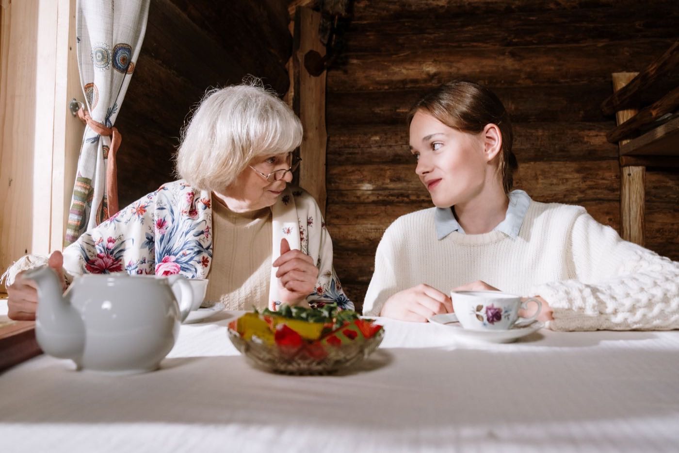 A companion sharing tea and warm conversation with an older woman at home